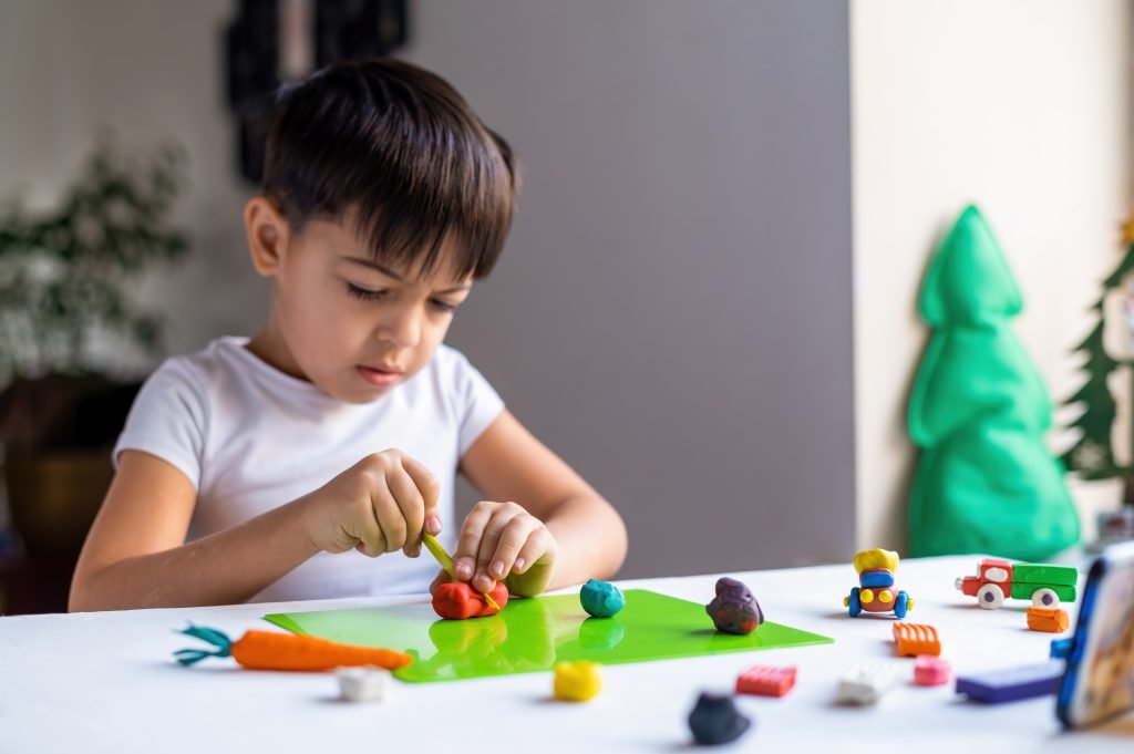 Child playing with clay and building blocks, showing sensory play for child development.
