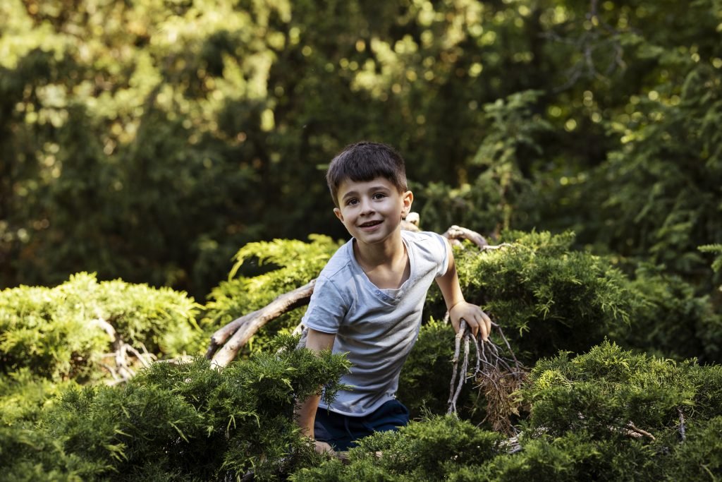 Indian child exploring outdoors, holding a butterfly, representing benefits of outdoor play for kids.
